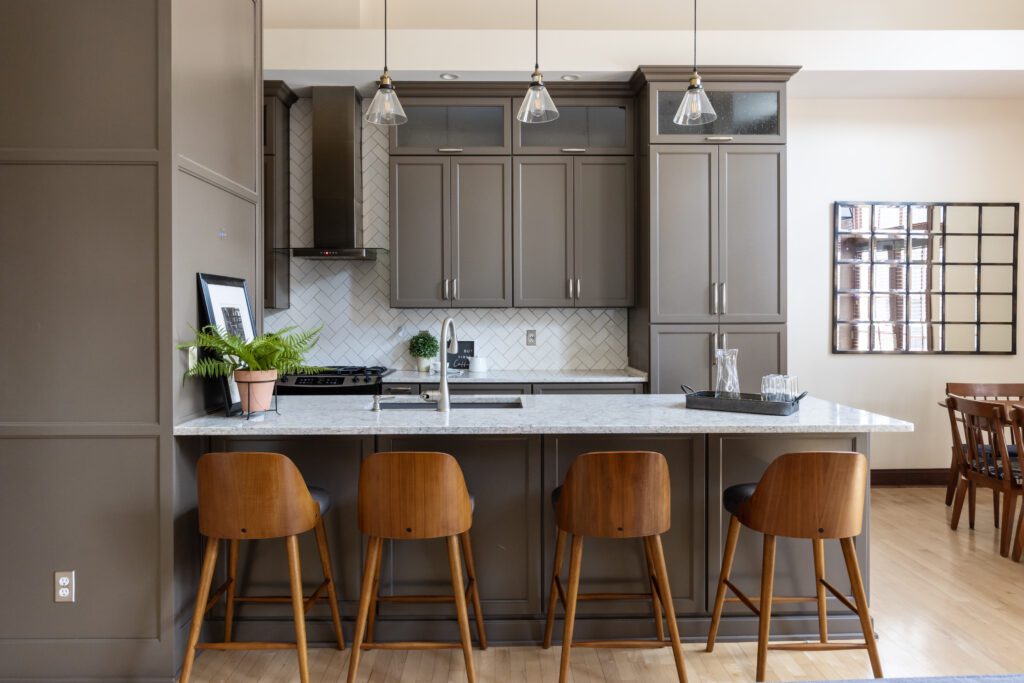 Listing photo of a luxury kitchen in neutral colors with breakfast bar, chairs and pendant lights.