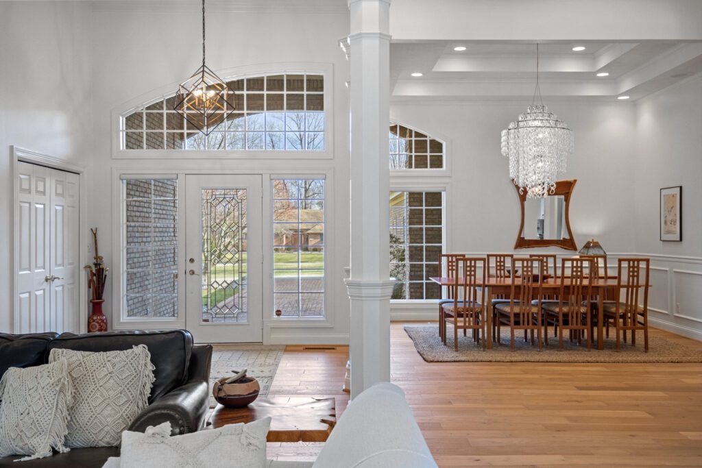 A glass-walled foyer and dining room with modern chandelier.